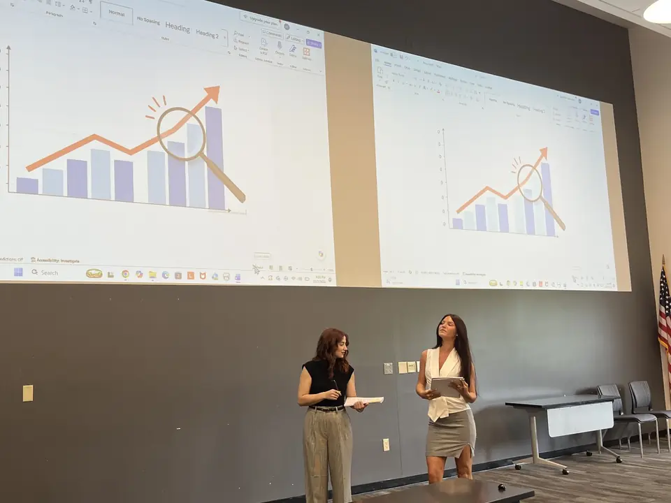 Dos estudiantes presentan un análisis de datos ante el cliente